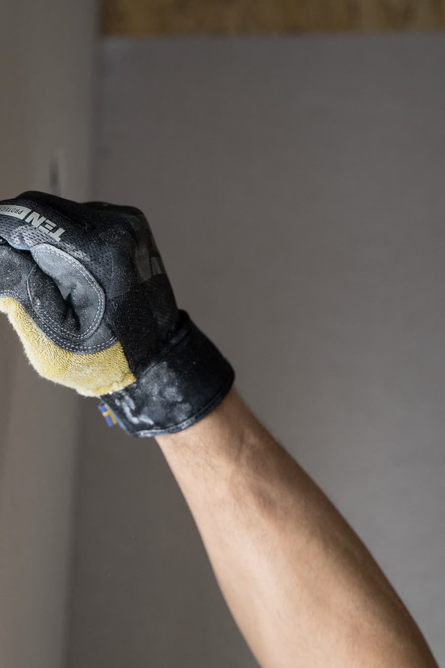 A gloved hand smoothing filler along the edge of an interior wall