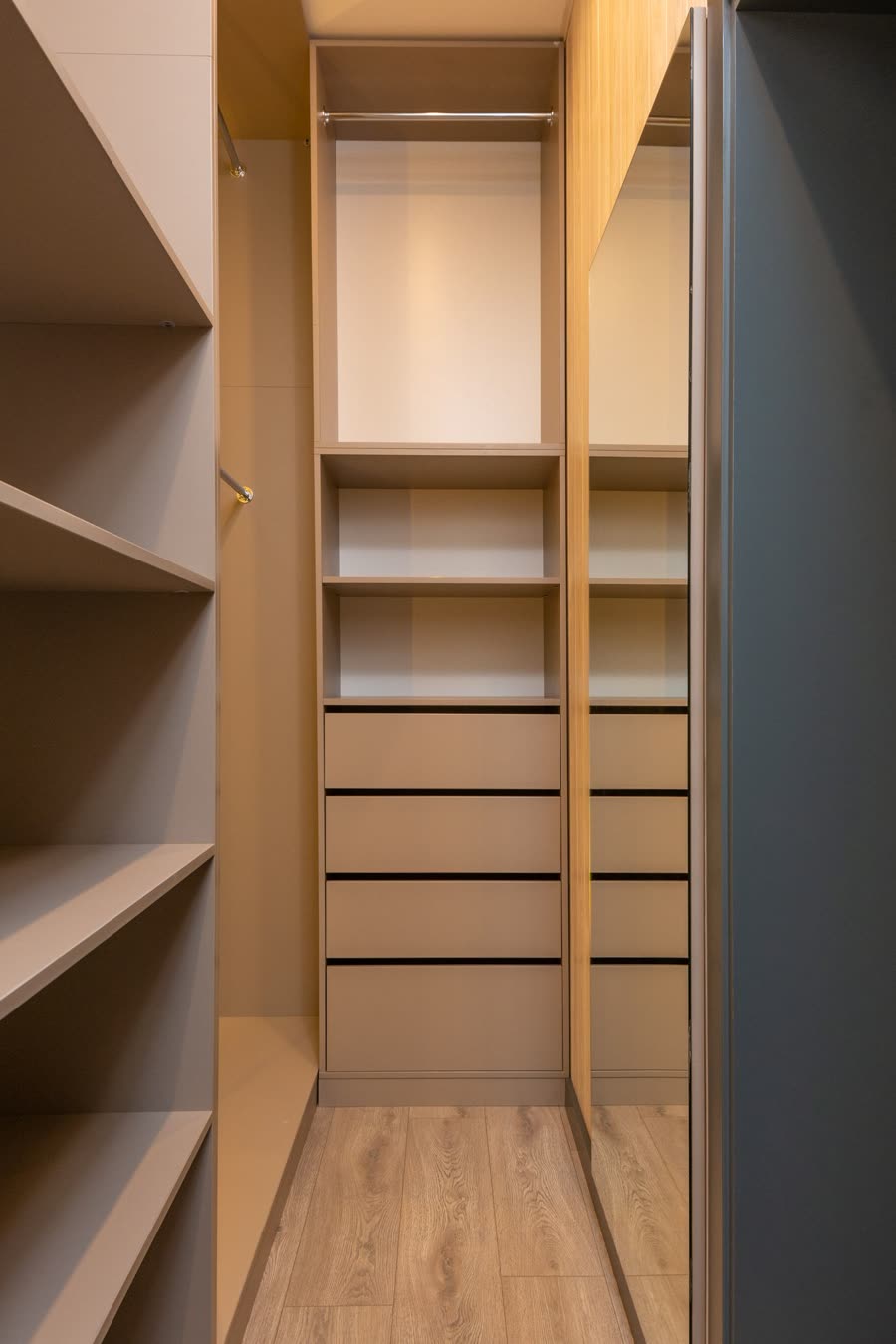 A fitted wardrobe interior in warm wood with open shelves and drawers