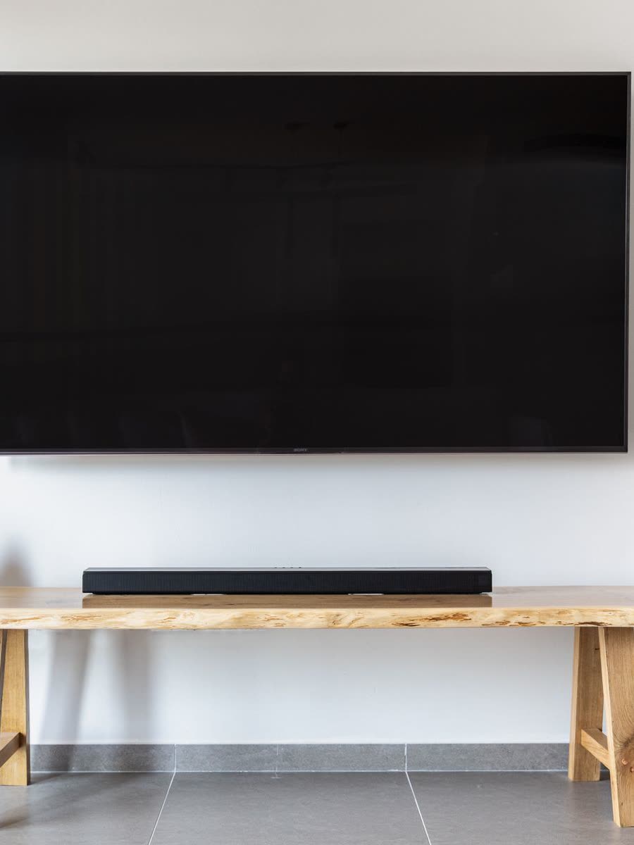 A wall-mounted flat-screen television above a live-edge wooden console in a bright room